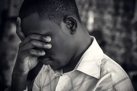 A young man praying, head in his hand
