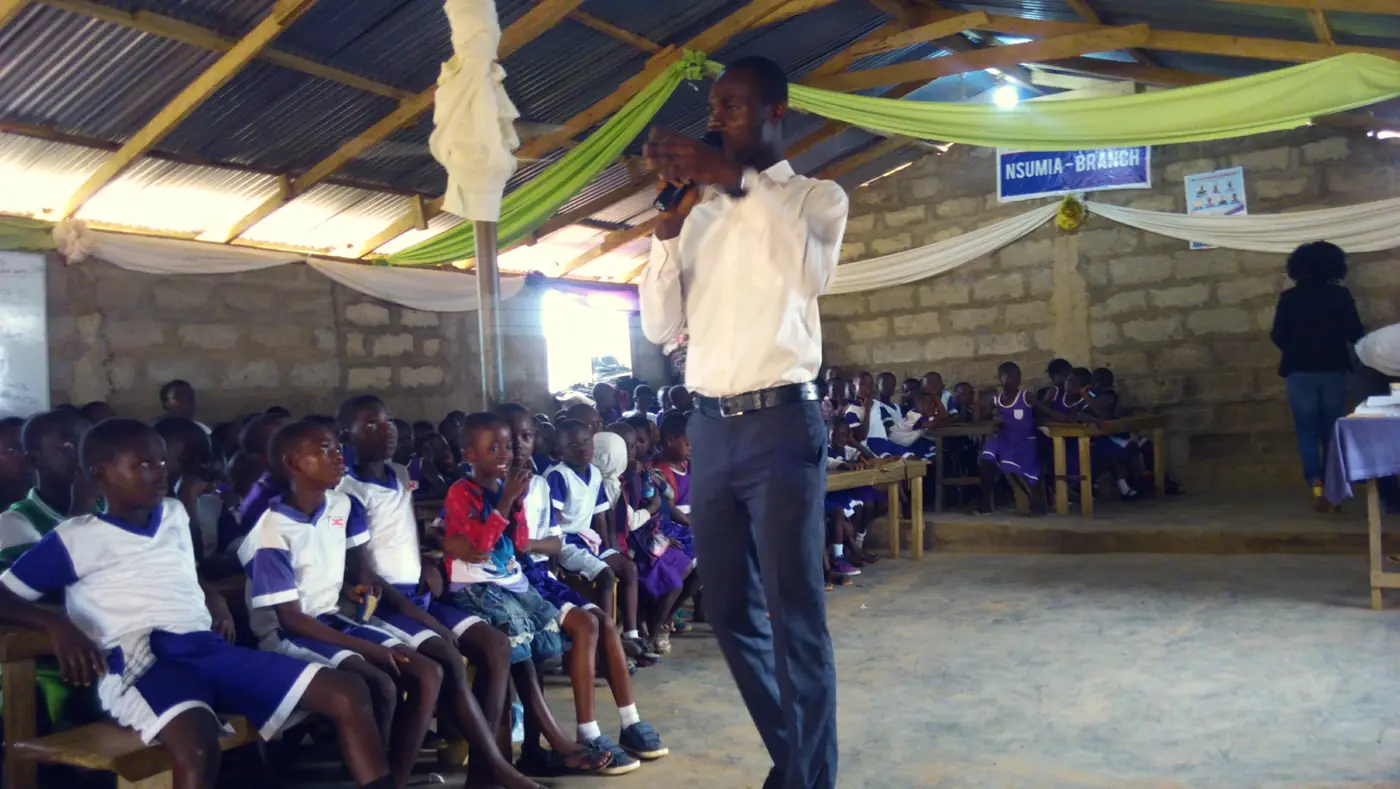 A BYM leader teaching students in a school hall