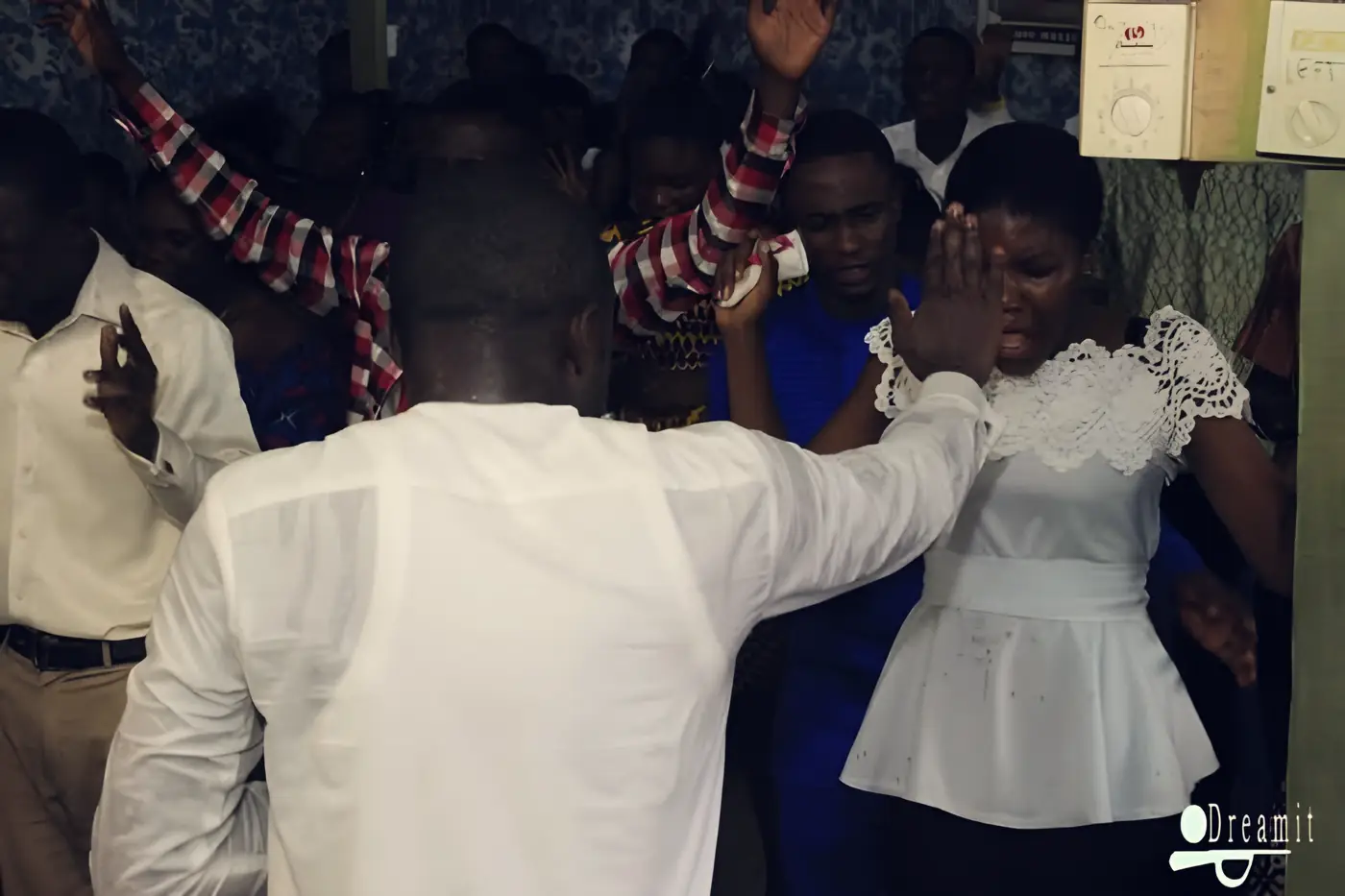 A leader praying over a young woman with hands raised around them